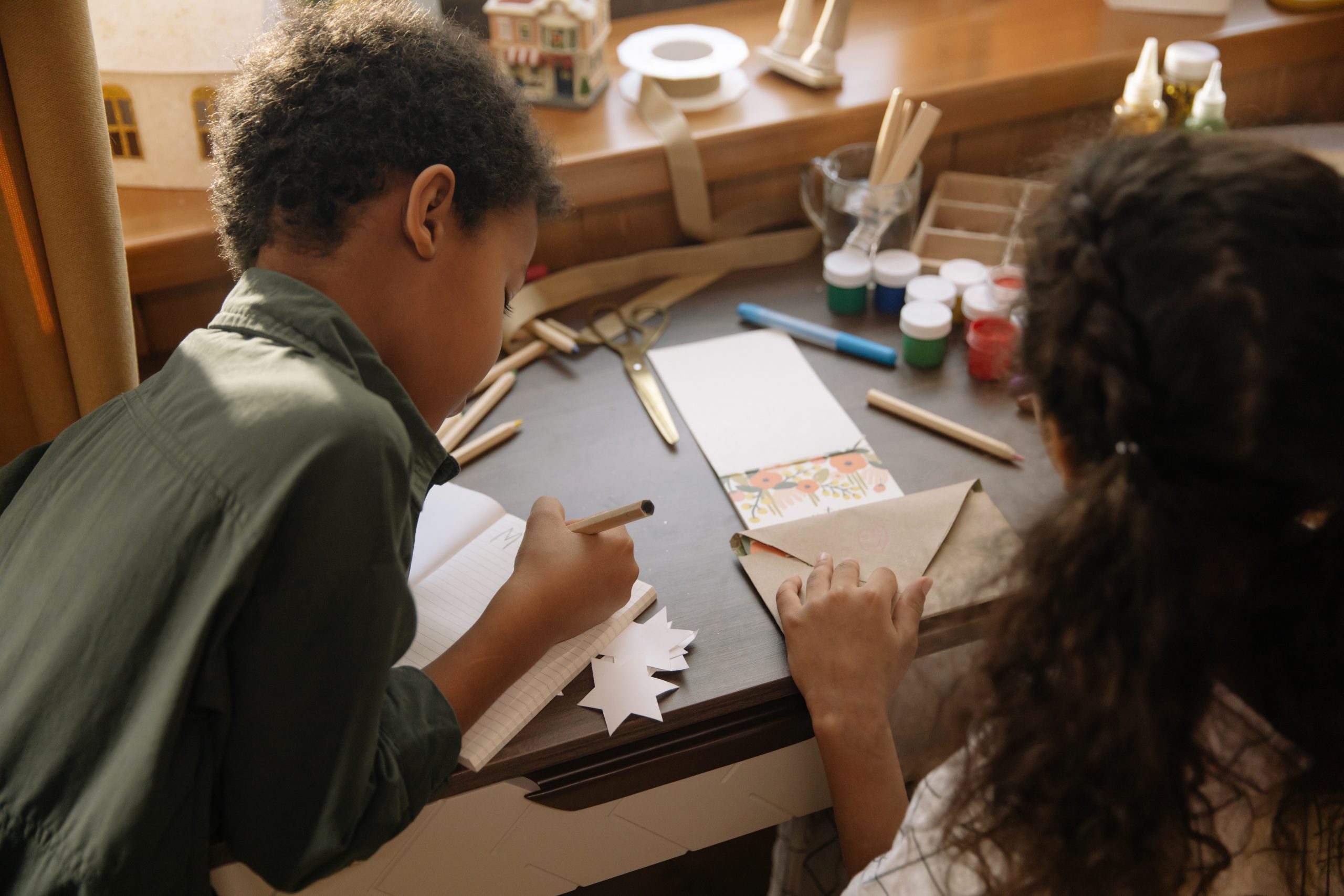 Duas crianças sentadas de costas fazendo atividades de artesanato